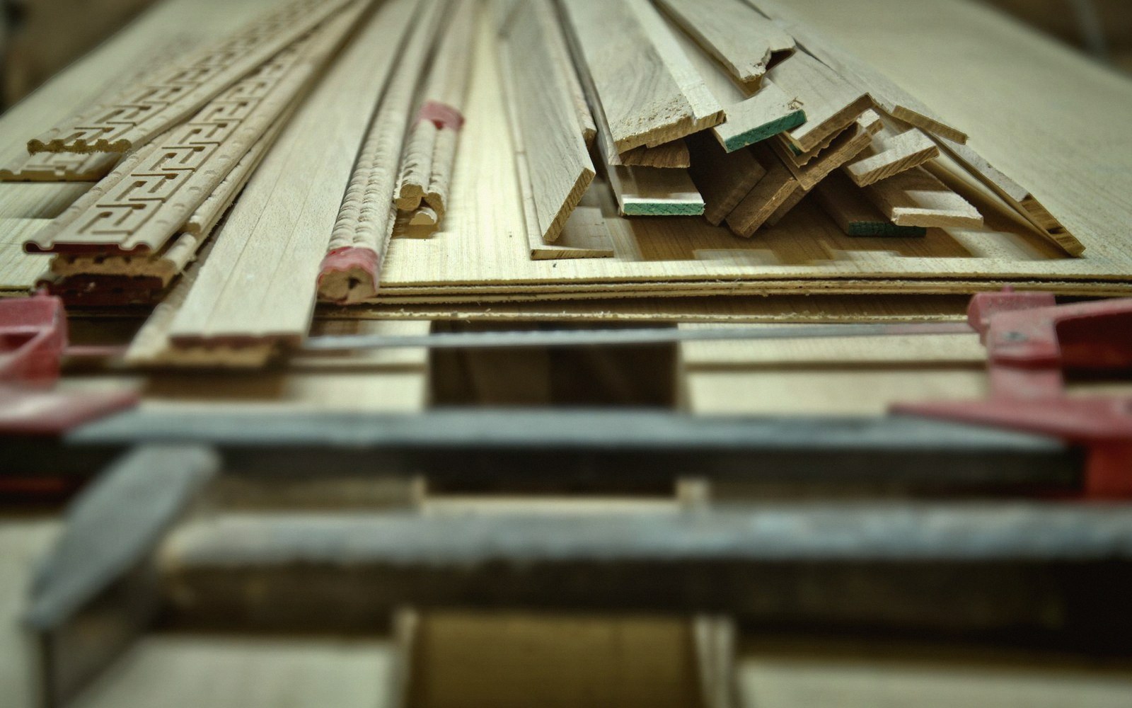Wooden moulding strips and decorative trim stacked together on a workshop bench