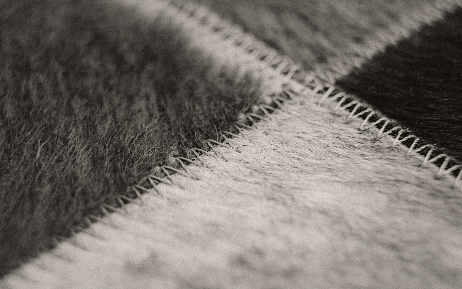 Close-up of zigzag stitched seams joining patches of light and dark cowhide