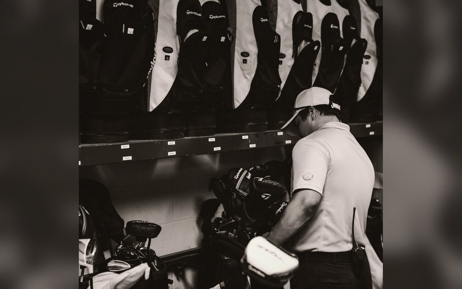 Staff member sorts golf bags on a storage shelf in a pro shop